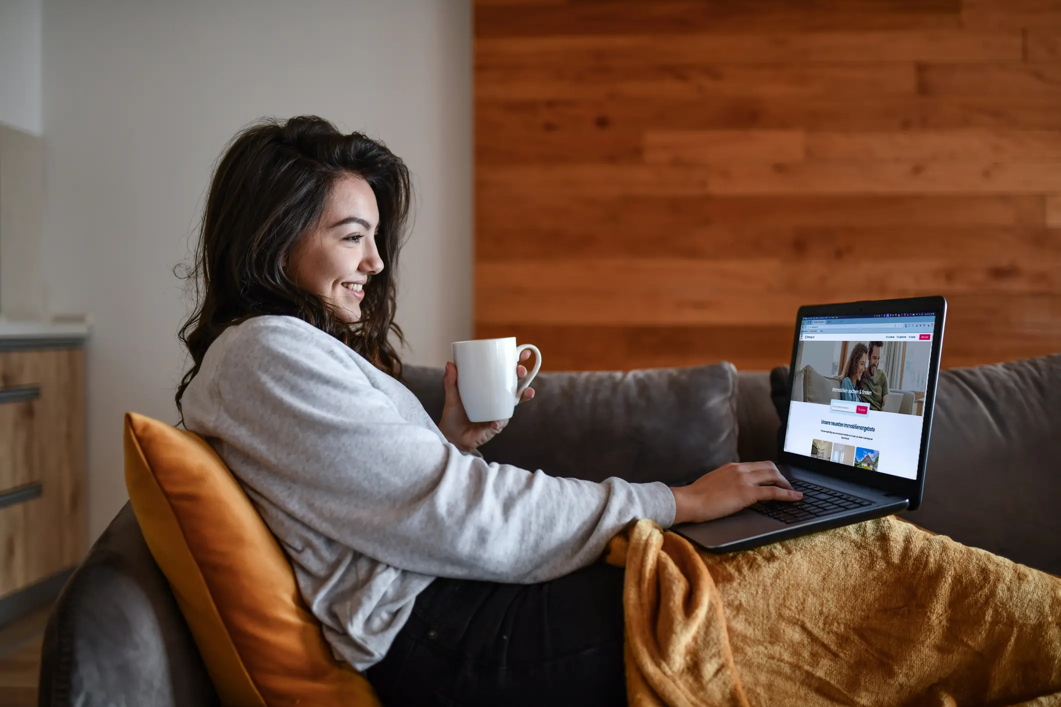 Wohnglück, Frau mit Laptop, die auf der Immobilienplattform sich Objekte ansieht.